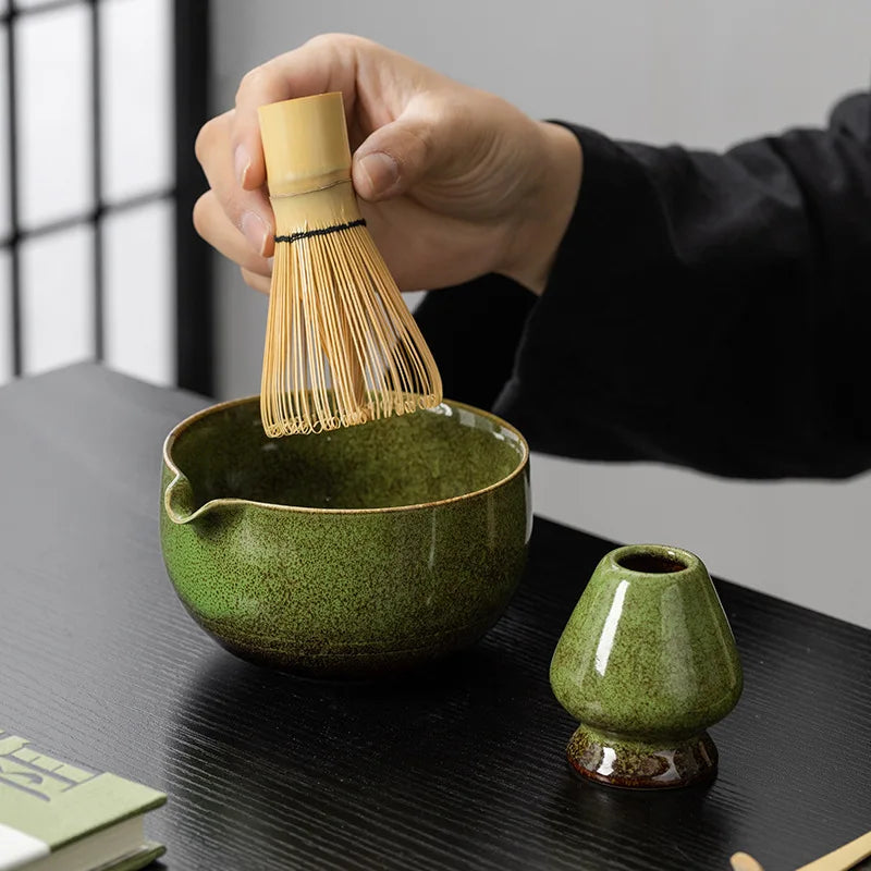 Whisking matcha in the green glazed bowl beside its whisk rest